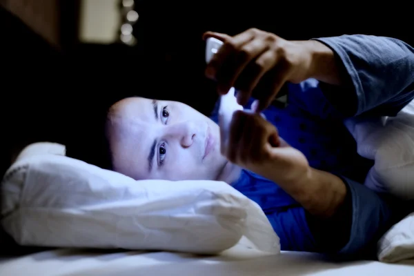 Hombre usando el teléfono móvil en la cama — Foto de Stock