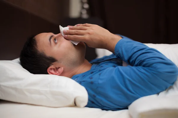 Ill uomo soffia il naso a letto — Foto Stock