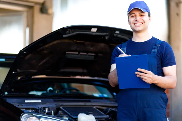 Mechanic writing on a clipboard — Stock Photo, Image