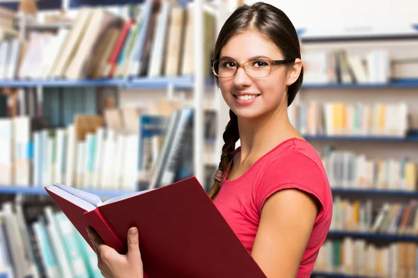 Mulher lendo um livro em uma biblioteca — Fotografia de Stock