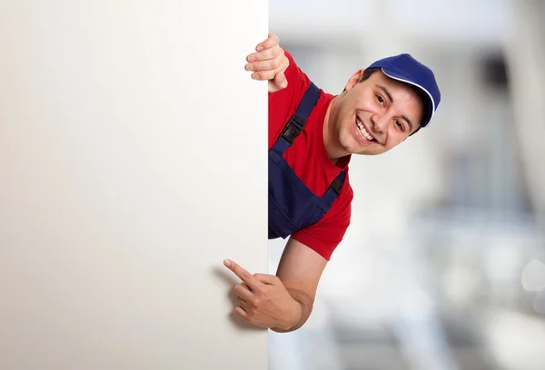 Trabajador señalando con el dedo a un tablero en blanco — Foto de Stock