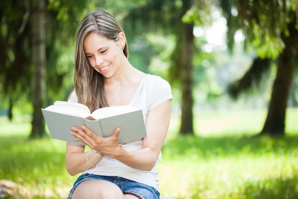 Genç gülümseyen kadın kitap okuma — Stok fotoğraf