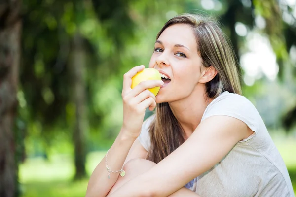 Kvinna äta ett äpple i parken — Stockfoto