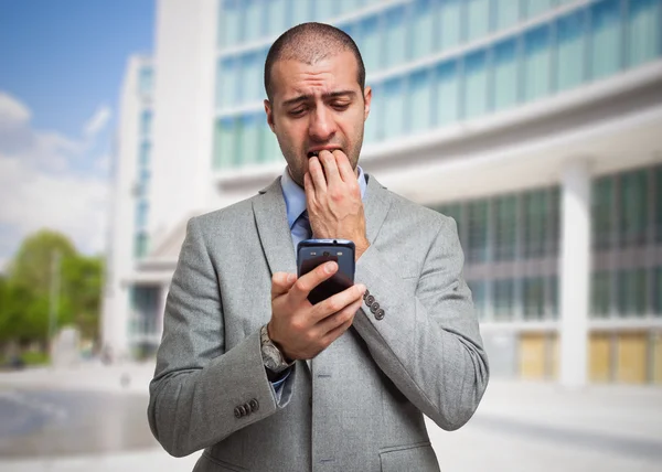 Scared man looking at his mobile phone — Stock Photo, Image