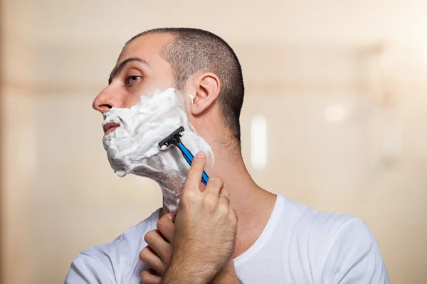 Мужчина, сбривающий бороду бритвой — стоковое фото