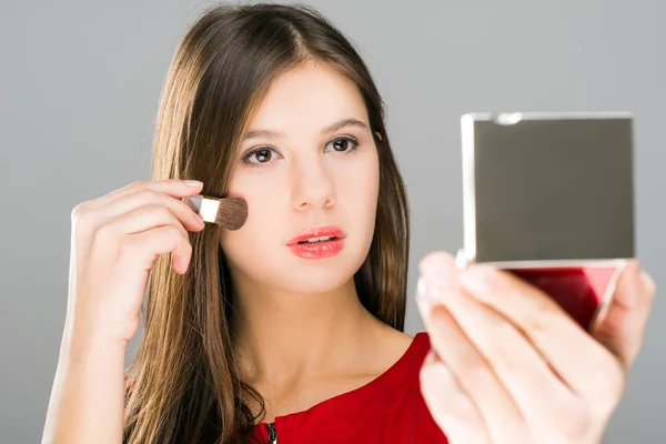 Woman applying makeup looking in her mirror — Stock Photo, Image