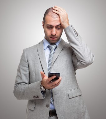 Şaşırmış adam akıllı telefona bakıyor.