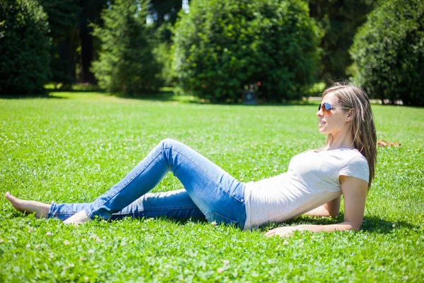 Usmívající se žena sedí na trávě — Stock fotografie