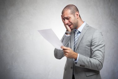 Depressed man reading document clipart