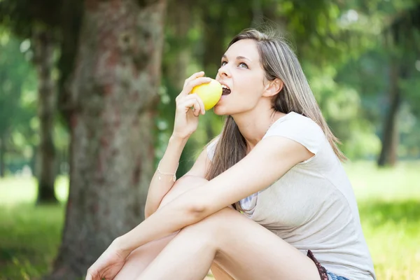 Woman eten apple in park — Stockfoto