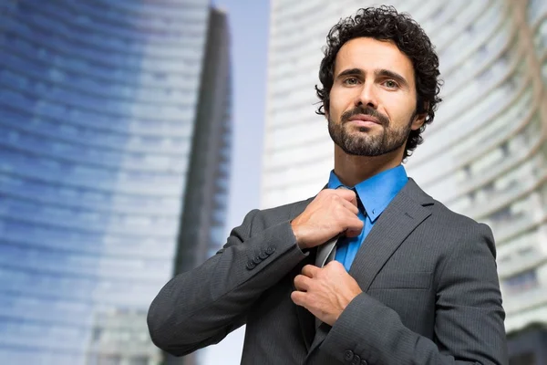 Красивый бизнесмен регулирует галстук — стоковое фото