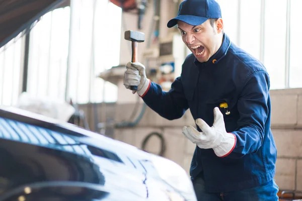 Mecánico enojado rompiendo motor de coche — Foto de Stock