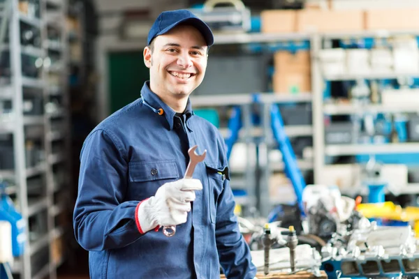 Worker in shop holding wrench — Stock Photo, Image