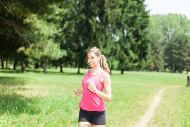 Genç bir kadın dışarıda koşuyor.
