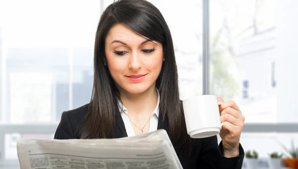 Frau liest Zeitung beim Kaffeetrinken — Stockfoto