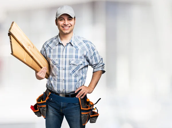 Carpintero sonriente sosteniendo tablones de madera — Foto de Stock