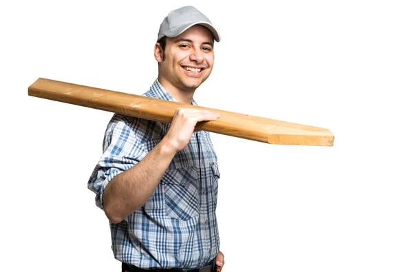 Carpintero sonriente sosteniendo tablón de madera — Foto de Stock