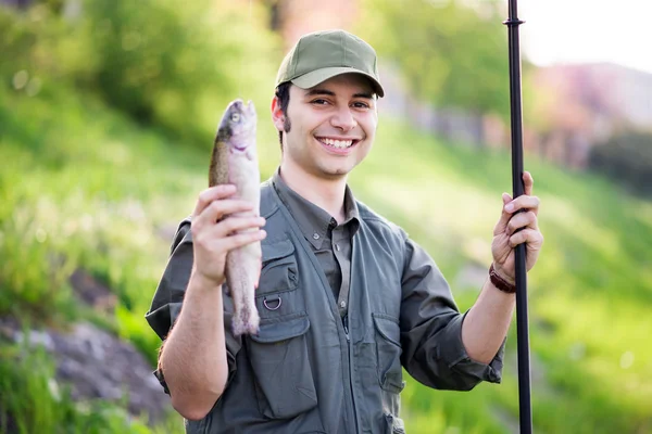 Pescatore sorridente che tiene un pesce — Foto Stock