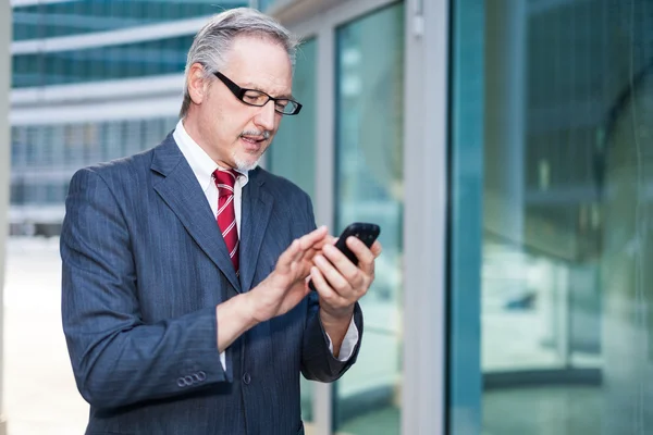 Usmívající se muž pomocí svého mobilního telefonu — Stock fotografie