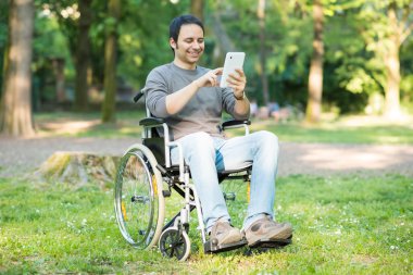 Adam tekerlekli sandalyede tablet kullanma