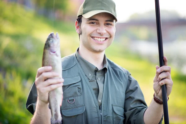 Улыбающийся рыбак держит рыбу — стоковое фото