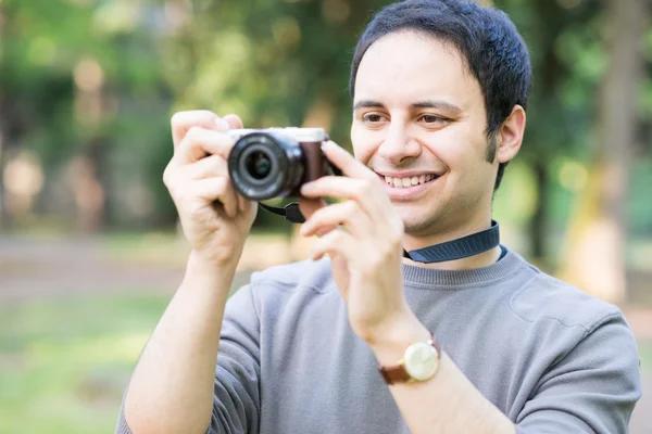 Sorrindo homem usando uma câmera sem espelho — Fotografia de Stock