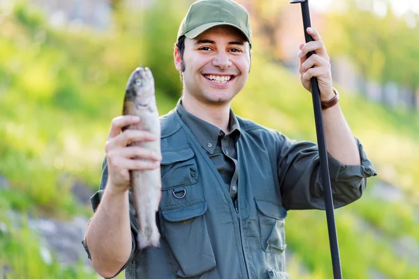 Pescatore sorridente che tiene il pesce — Foto Stock