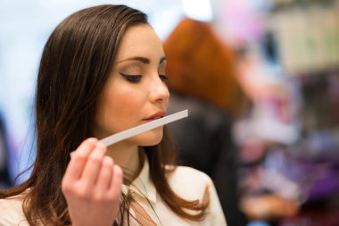 Woman smelling a perfume in a shop clipart