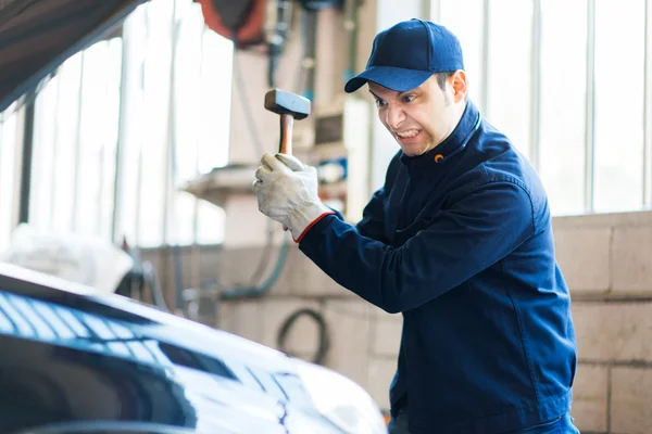 Angry mechanic smashing car engine — Stock Photo, Image