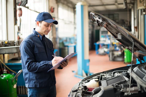 Mechanic writing on clipboard — Stock Photo, Image