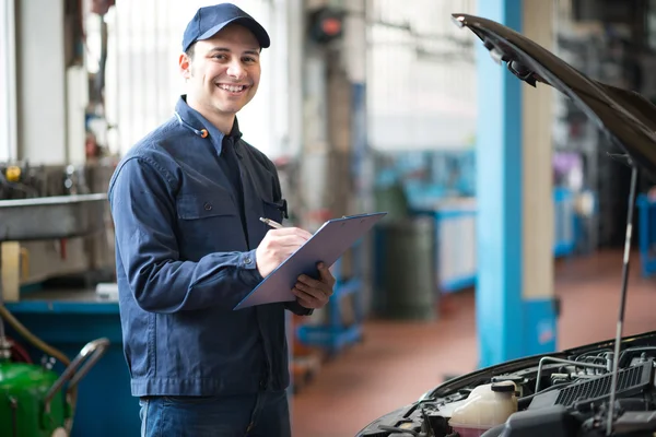 Mechanic writing on a clipboard — Stock Photo, Image