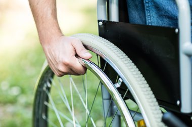 Male hand on the wheel of wheelchair clipart