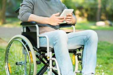 Tablet üzerinde tekerlekli sandalye kullanan adam