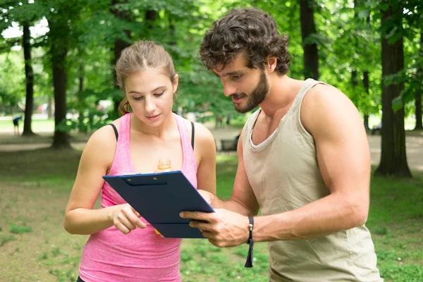 Man showing training table to woman — Stock Photo, Image