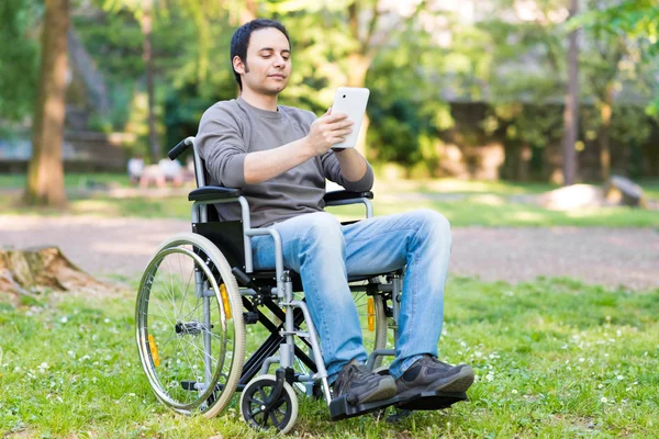 Homem usando uma cadeira de rodas em um parque — Fotografia de Stock