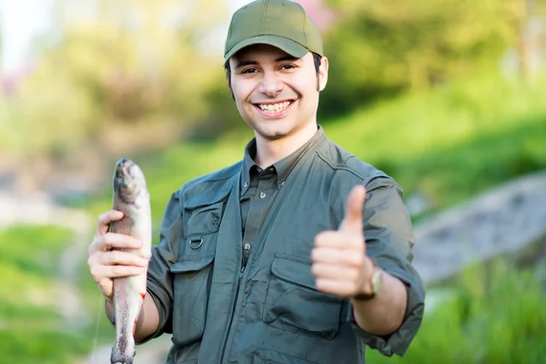 Pescador feliz segurando um peixe — Fotografia de Stock