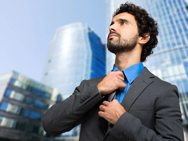 Handsome businessman adjusting his tie — Stock Photo, Image