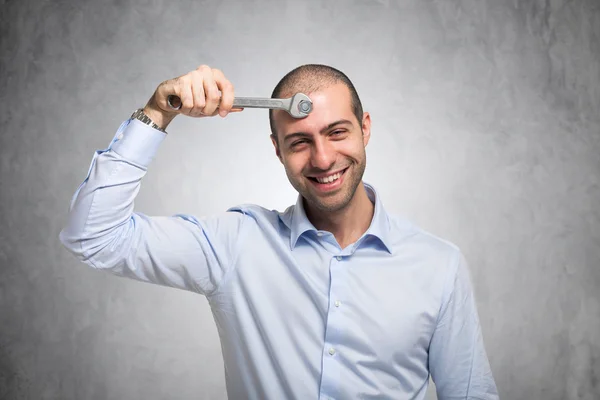 Mann benutzt Schraubenschlüssel, um seinen Verstand zu justieren — Stockfoto
