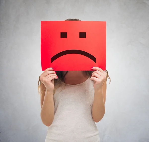 Woman holding a sad emoticon — Stock Photo, Image