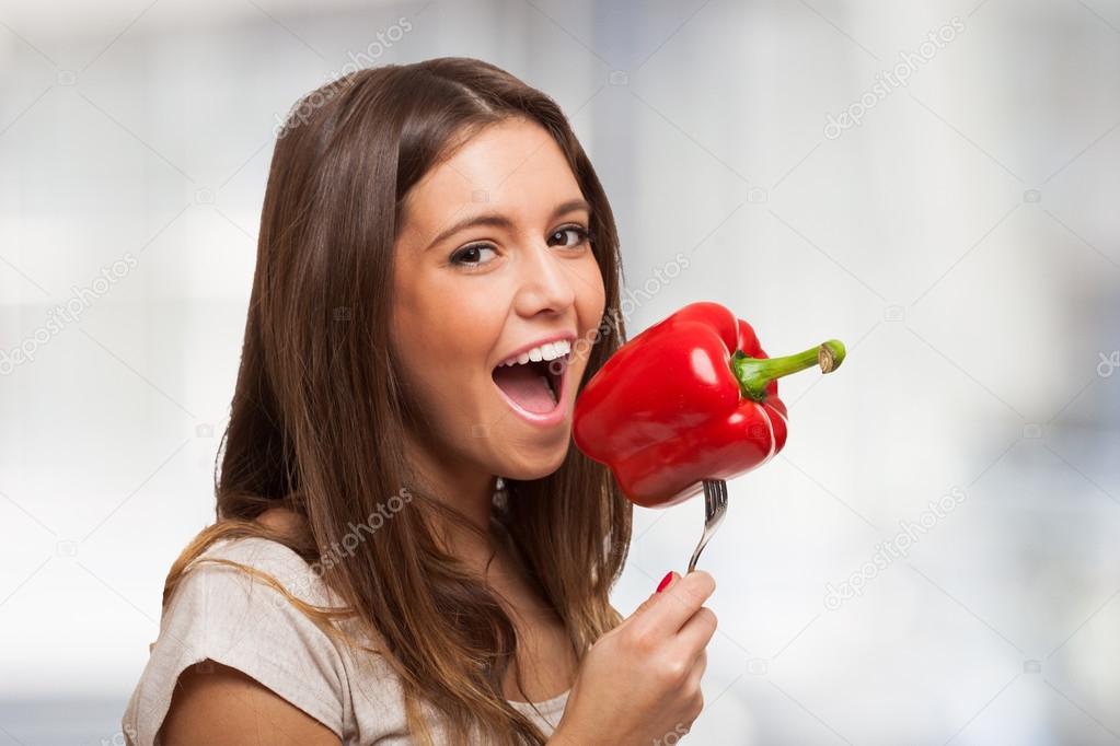 Woman trying to eat a pepper on fork