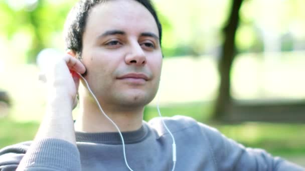 Homme écoutant de la musique dans un parc — Video