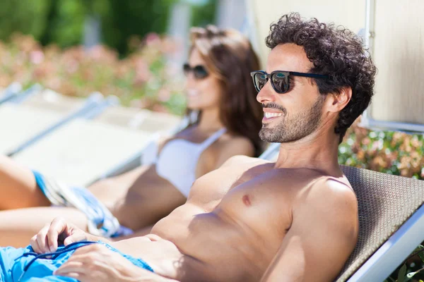 Couple relaxing on deck-chairs — Stock Photo, Image