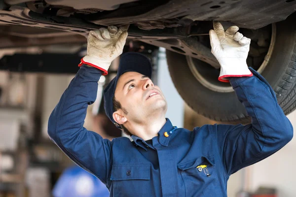 Mechanic checking condition lifted car — Stock Photo, Image