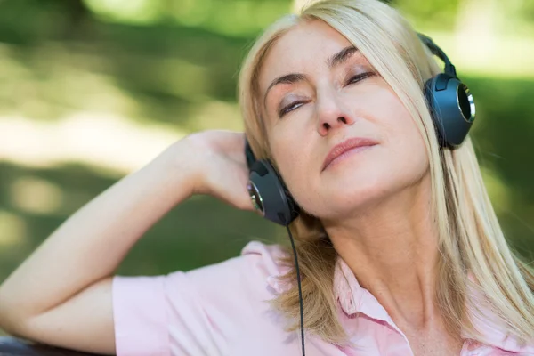 Kypsä nainen kuuntelee musiikkia — kuvapankkivalokuva