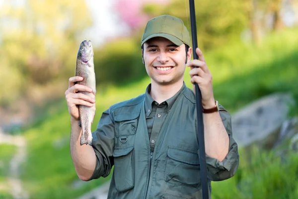 Pescatore sorridente che tiene un pesce — Foto Stock