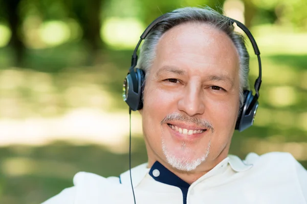 Зрелый улыбающийся мужчина слушает музыку — стоковое фото