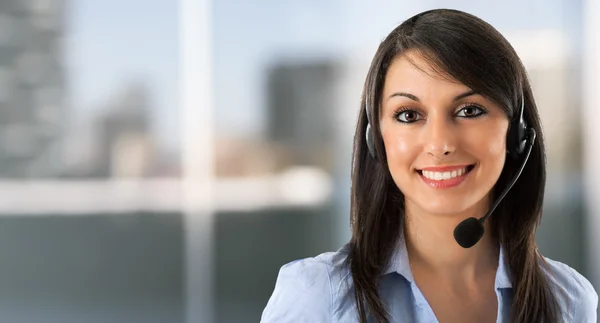 Mulher sorridente usando um fone de ouvido — Fotografia de Stock