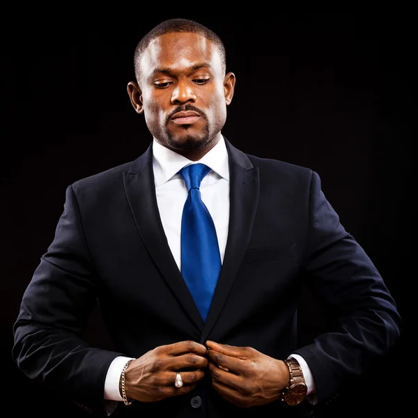 African businessman adjusting jacket — Stock Photo, Image