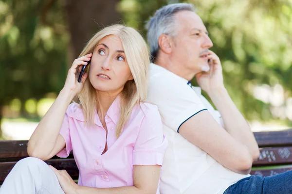 Äldre par talar på telefoner — Stockfoto