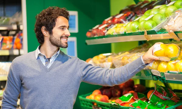 Hombre recogiendo verduras en la tienda de comestibles — Foto de Stock